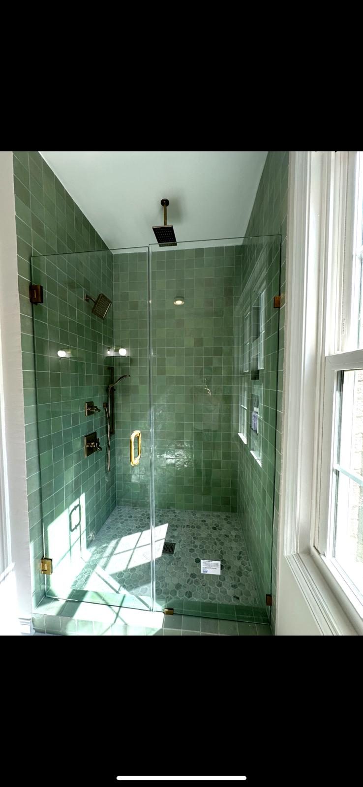 Green zellige tile walk-in shower with glass enclosure and brass fixtures
