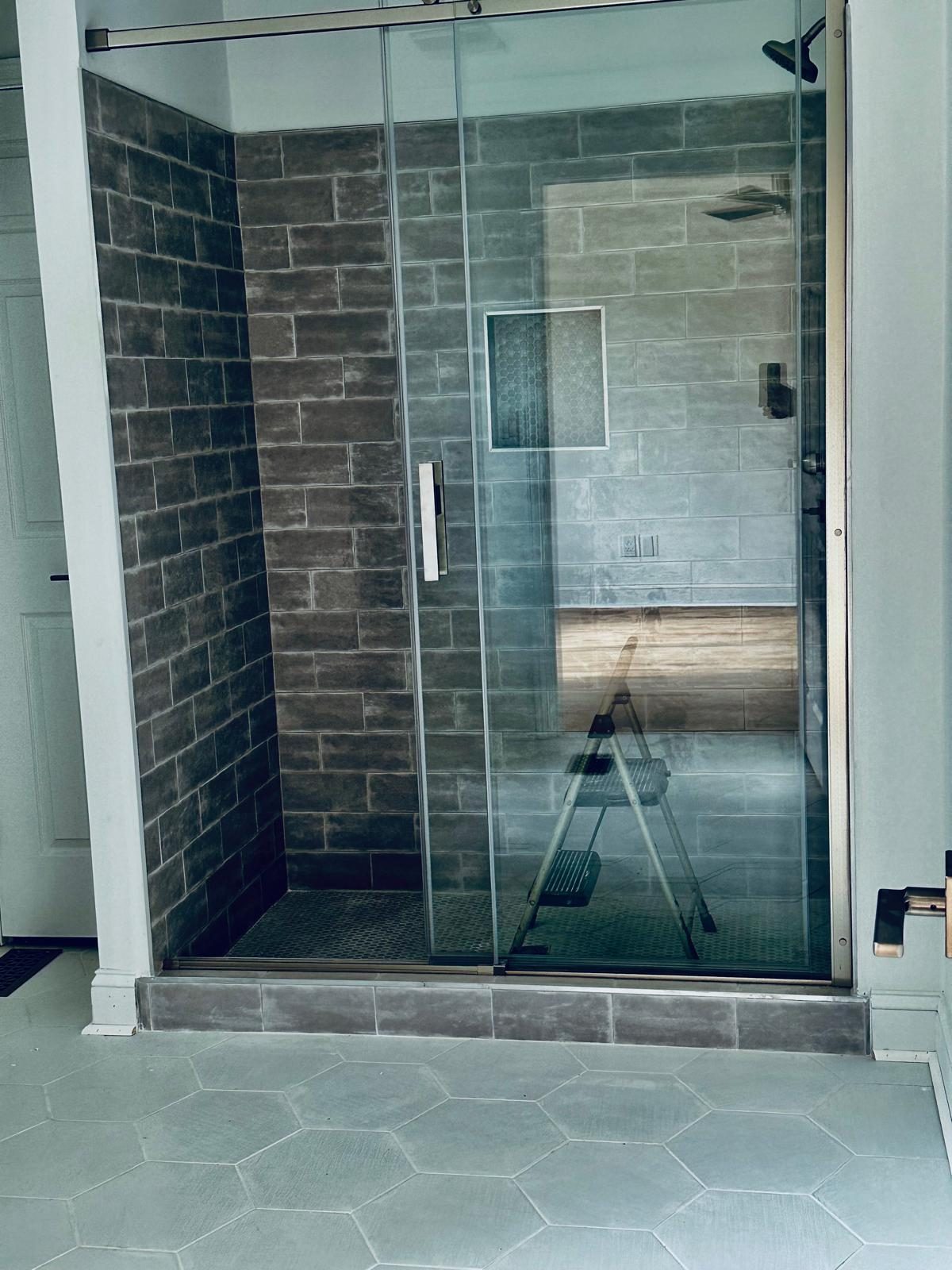 Modern shower with dark textured subway tile and hexagon floor