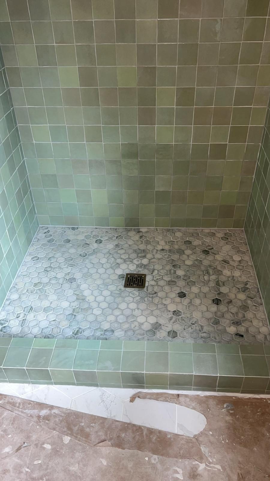 Green tile shower with hexagon marble mosaic floor